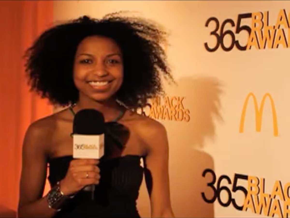 Chelsea on the mic in front of the McDonald's 365 Black Awards backdrop