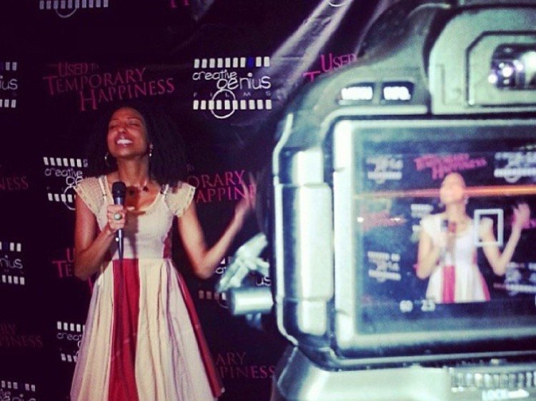 Chelsea on the mic at the Used to Temporary Happiness premiere, framed on a camera screen